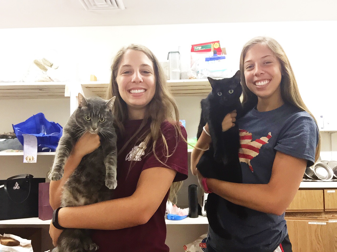 two girls hold cats
